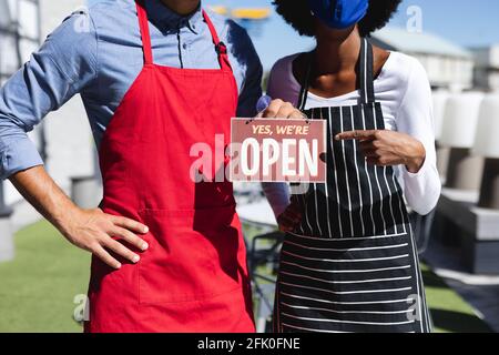 Sezione centrale di diversi camerieri maschili e femminili che indossano maschere facciali cartello aperto Foto Stock