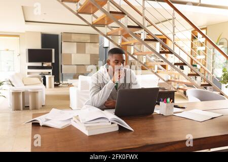 Giovane afro-americano che usa il laptop mentre studia a casa Foto Stock