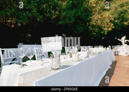 Un cartello vuoto si erge su un tavolo per le vacanze splendidamente servito coperto con una tovaglia bianca Foto Stock