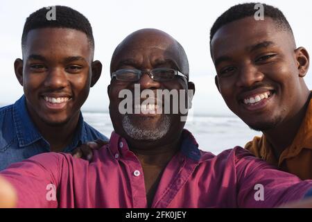 Ritratto di padre afroamericano e dei suoi due figli prendendo un selfie in spiaggia Foto Stock