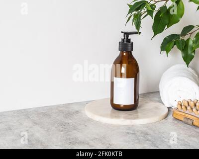 Mockup di bottiglie di vetro marrone per prodotti cosmetici, asciugamani di cotone e massaggiatore in legno. Vista frontale. Spazio copia. Prodotti cosmetici mock up. Blogging minimo Foto Stock
