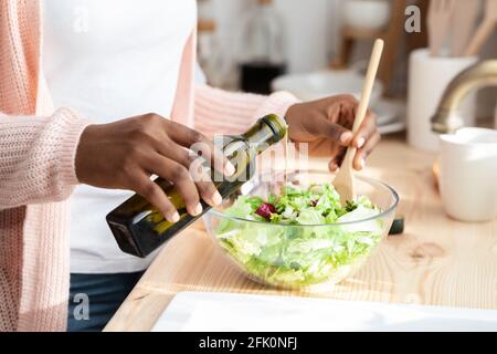 Nutrizione sana. Closeup Shot di Unriconoscable Donna Nera cucinare insalata di verdure fresche in cucina, African American Housewife aggiunta di condimenti OL Foto Stock