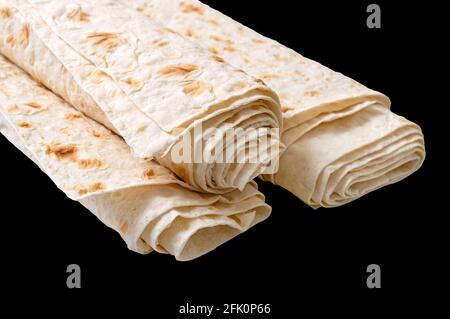 Pane pita arrotolato isolato su fondo nero. Lavash - gustoso e sano pane piatto armeno e turchi senza lievito Foto Stock