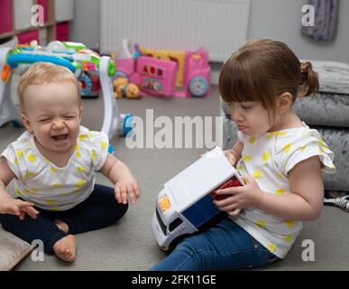 Un bambino giovane grida come un bambino più grande prende a. giocattolo lontano da lei Foto Stock