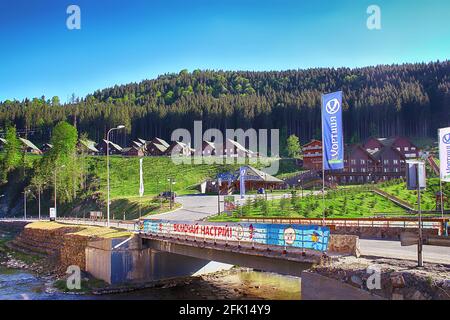 Bukovel, Ucraina - 11 maggio 2013: Case di legno nella stazione sciistica e ponte sul torrente Foto Stock