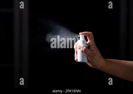 Primo piano mano di spruzzatura di alcool portatile spray disinfettante antibatterico flacone disinfettante contro la diffusione COVID-19. Superfici di igienizzazione Concept p Foto Stock