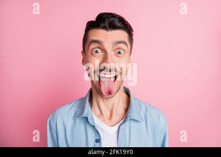 Primo piano ritratto di simpatico ragazzo divertente e allegro che mostra la lingua isolato su sfondo color pastello rosa Foto Stock