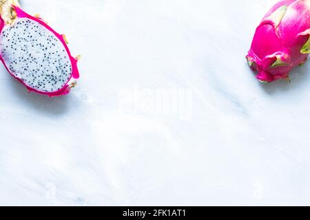 Frutta di drago rosa brillante tagliata a metà su texture grigie sfondo Foto Stock