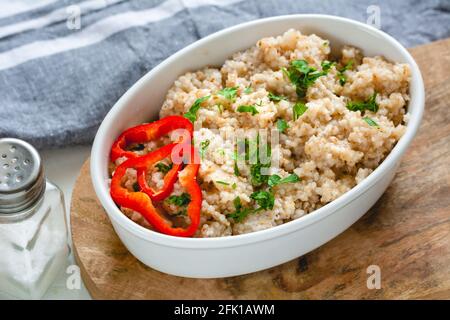 Grani di orzo cotti in una ciotola bianca. Cibo sano Foto Stock