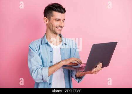 Ritratto fotografico giovane imprenditore che lavora su un computer portatile sorridente digitando testo navigazione internet isolato colore rosa pastello sfondo Foto Stock