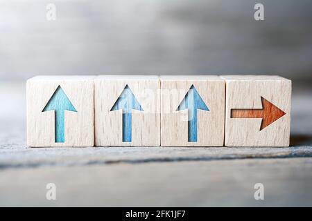 Frecce con direzioni diverse sui blocchi di legno su una tavola - stare in piedi fuori dal concetto di folla Foto Stock