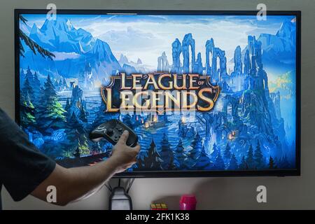 Uomo che tiene il controller di vapore davanti a uno schermo di caricamento Il popolare RPG MMORPG campionato di leggende molto amato gioco popolare con milioni di online Foto Stock