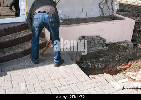 Dnepropetrovsk, Ucraina - 03.26.2021: Un lavoratore spazza su sporcizia dopo la sostituzione dei tubi fognari. Foto Stock