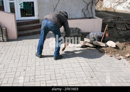 Dnepropetrovsk, Ucraina - 03.26.2021: Un lavoratore spazza su sporcizia dopo la sostituzione dei tubi fognari. Foto Stock