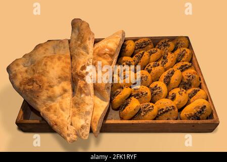 Focaccia pane e focaccine appena sfornate con olive pate in vassoio di legno, isolato su sfondo beige Foto Stock