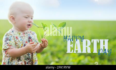 la bambina tiene germogli di soia giovani. Texte sur HAPPY Earth Day. Ambiente sostenibile, pianta Glycine max, soia, germoglio di soia che cresce soia o Foto Stock