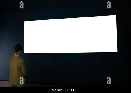 Donna che guarda a vuoto ampia parete interattiva display - schermata bianca concept Foto Stock