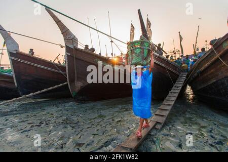 Un lavoratore sta scaricando pesce da pescherecci a strascico a Fishery Ghat a Chittagong. Foto Stock