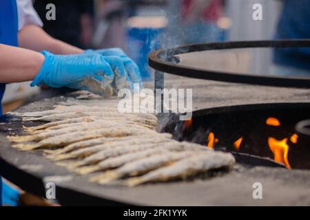 Chef cucina europeo odore di pesce in farina su braciere nero al festival del cibo Foto Stock