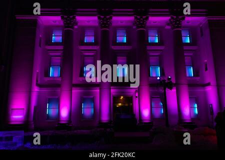 Edificio storico a quattro piani con colonne romane illuminate di notte luci viola brillanti che cambiano colore per un festival invernale Foto Stock