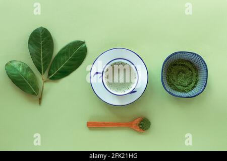 Tè verde matcha in una tazza bianca, tè in polvere e cucchiaio di legno, vista dall'alto. Bevanda sana. Disposizione piatta. Foto Stock