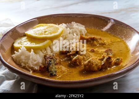 Curry africano di pollo conosciuto anche come kuku paka, servito con riso e limone a fette Foto Stock