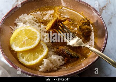 Curry africano di pollo conosciuto anche come kuku paka, servito con riso e limone a fette Foto Stock