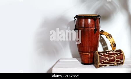 Composizione dello strumento etnico musicale. Maracas, tamburello, conga e tamburo etnico. Gli strumenti a percussione sono su sfondo bianco con palma Foto Stock