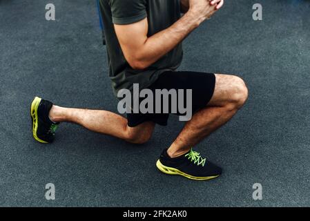 Atleta giovane e sano che fa squat sul parco giochi per strada. Giovane uomo che si esercita all'esterno. Primo piano. Foto Stock