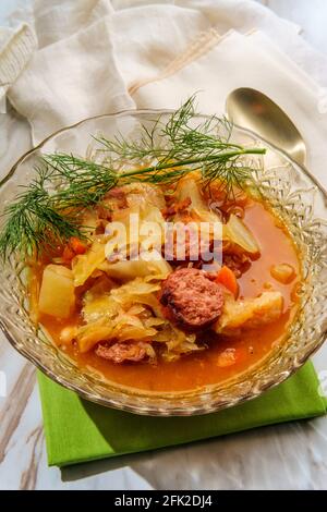 Stufato tedesco di kielbasa Oktoberfest con patate a cavolo e un bicchiere di vino bianco Foto Stock