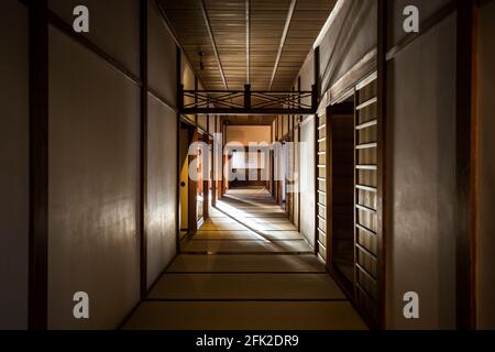 Albero di luce attraverso un corridoio ombreggiato e scarsamente illuminato con pavimento in tatami nel vecchio edificio giapponese samurai. Foto Stock