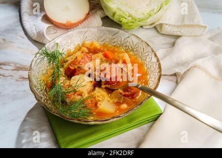 Stufato tedesco di kielbasa Oktoberfest con patate a cavolo e un bicchiere di vino bianco Foto Stock