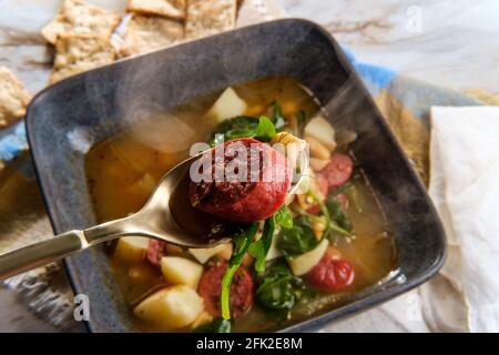 Zuppa polacca di fagioli kielbasa con patate e rucola servita con cracker multigrain Foto Stock