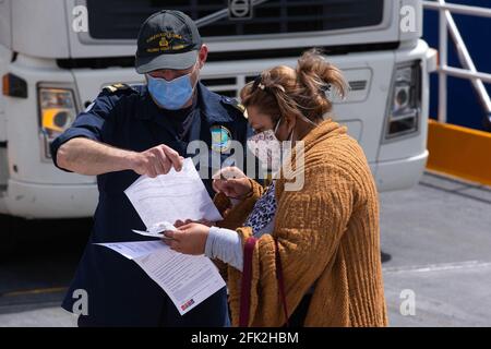 Pireo, Grecia. 27 Apr 2021. Un membro della Guardia Costiera greca controlla i documenti di viaggio di un passeggero a Pireo, Grecia, il 27 aprile 2021. In un discorso televisivo alla nazione la scorsa settimana, il primo ministro greco Kyriakos Mitsotakis ha affermato che i greci non potranno viaggiare liberamente durante la Pasqua cristiana ortodossa, che si celebrerà il 2 maggio, a causa della situazione epidemica ancora grave. Credit: Marios Lolos/Xinhua/Alamy Live News Foto Stock