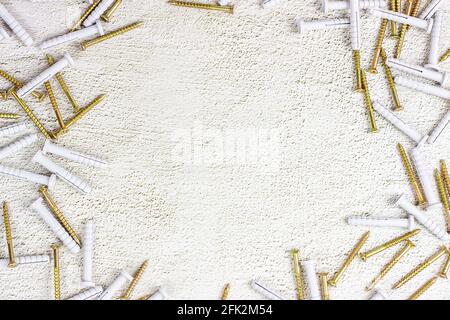 Molti tasselli in acciaio e plastica per la riparazione del telaio su fondo in cemento grigio chiaro con spazio di copia. Fai da te, miglioramento della casa e concetto di costruzione della casa. Foto Stock