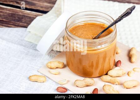 Burro di arachidi croccante fresco fatto in casa con noci su sfondo di legno chiaro in cucina. Foto Stock