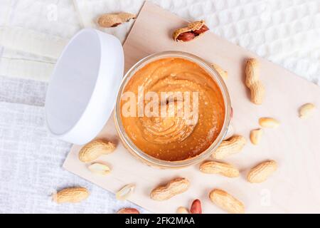 Vista dall'alto del fresco burro di arachidi croccante fatto in casa con noci su sfondo di legno chiaro in cucina. Foto Stock