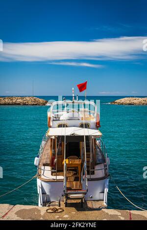 Barca bianca con bandiera turca ancorata nella baia dell'antica città di Side, Turchia, vista posteriore Foto Stock