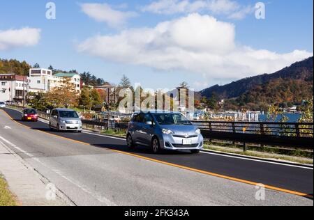 Nikko, Giappone - 24 ottobre 2016: Auto che guidano lungo la riva del lago Chuzenji nel parco nazionale di Nikko Foto Stock