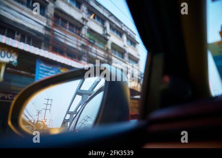 Uno specchio ad ala dell'automobile con il bagliore dei fari e dei riflessi degli edifici. Foto Stock