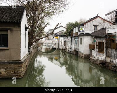 Canale d'acqua nella città vecchia di Suzhou fiancheggiata da mura bianche case Foto Stock