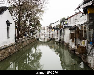 Canale d'acqua nella città vecchia di Suzhou fiancheggiata da mura bianche case Foto Stock