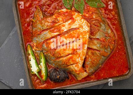 Il curry bianco del masala del pomfret, fatto nello stile dell'india del sud con salsa rossa spessa e guarnito con il peperoncino verde, le foglie del curry e il tamarindo del malabar organizzano Foto Stock