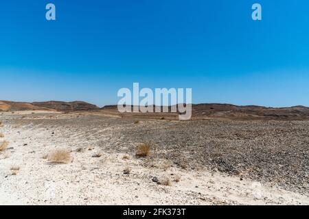 Una vista dal cratere del Ramon Crater. Vista arida del deserto. Sabbie bianche e un orizzonte di cielo blu. Negev, Israele. Foto di alta qualità Foto Stock