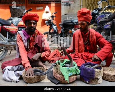 I tradizionali incantatori indiani di serpenti che intrattengono il cocciato nella città vecchia di Varanasi, India. Foto Stock