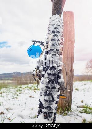 Ciclismo invernale. Dettaglio della ruota posteriore di montagna con neve tra le impugnature alte. Sport inverno sfondo. Foto Stock