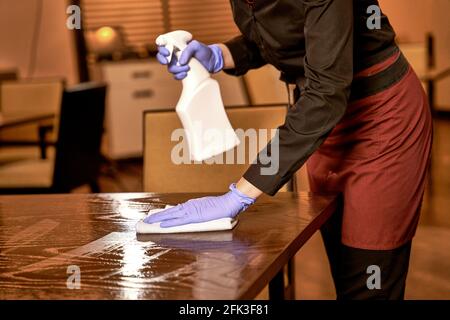 Operaio del ristorante che lava un tavolo spruzzato con un panno Foto Stock