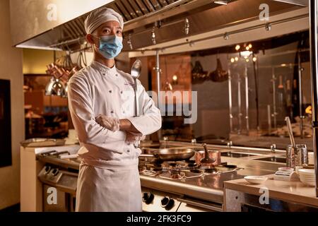 Cucina asiatica piegando le braccia e guardando in lontananza Foto Stock