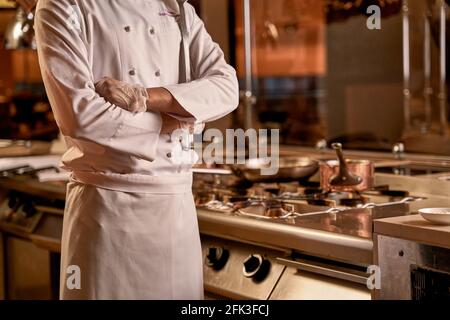 Braccia incrociate di chef ristorante accanto al fornello Foto Stock