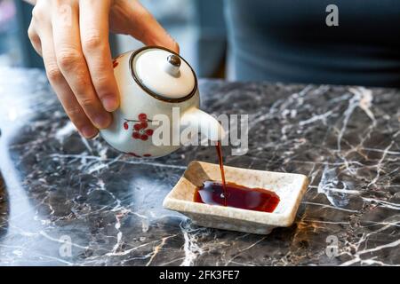 Una donna che mangia cibo giapponese sta versando salsa di soia Foto Stock